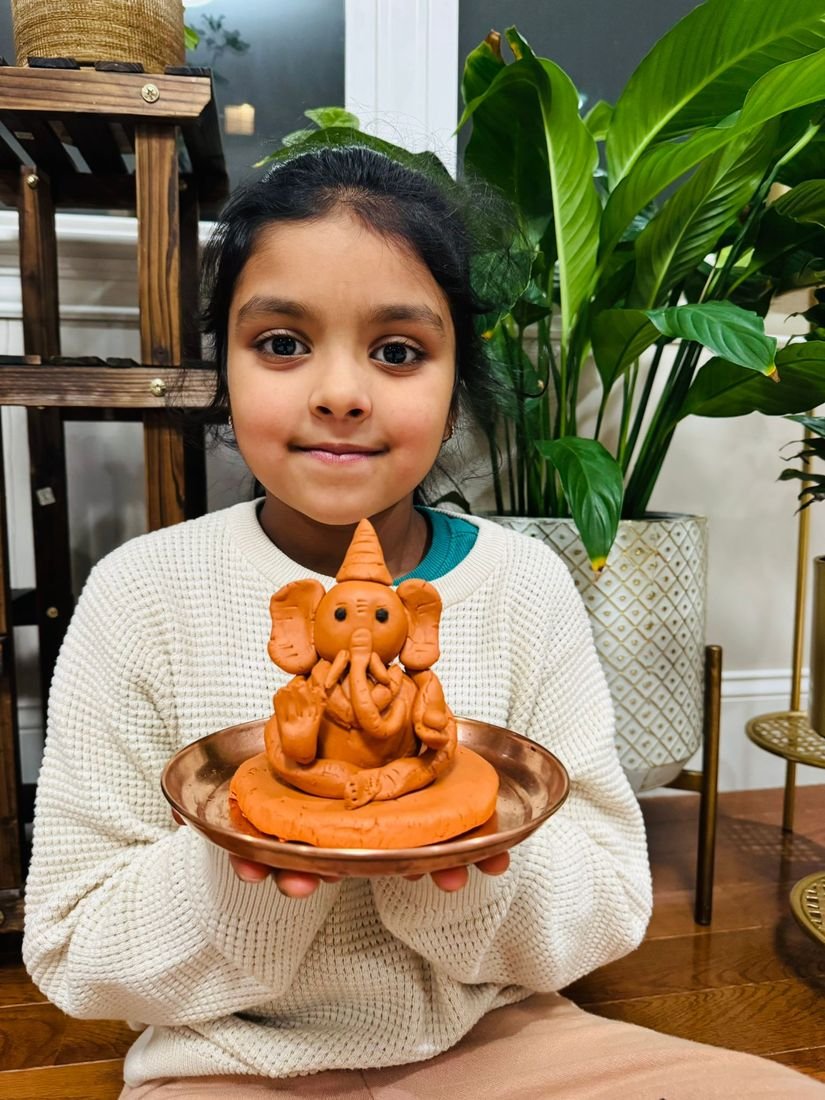 A girl holding the clay Ganesha she made