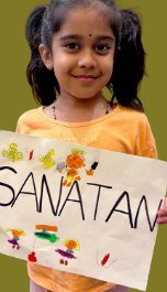 A girl holding a hand-painted SANATAN sign